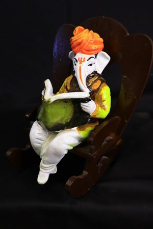 Ganesha (Ganpati) seated in a wooden rocking chair reading a book