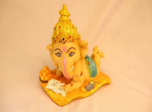 Ganesha (Ganpati) figurine reading a book on golden cushion, hand-painted