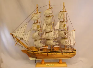 Vintage handcrafted wooden sailing ship model with cloth sails and detailed rigging on a wooden stand